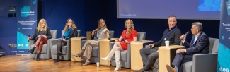 Three professionals seated on a stage in a panel discussion setting.