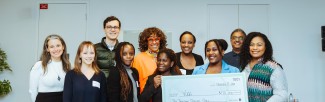 Group of people standing in front of a large cheque