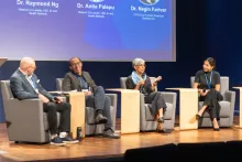 Four individuals on a stage in a panel setting 